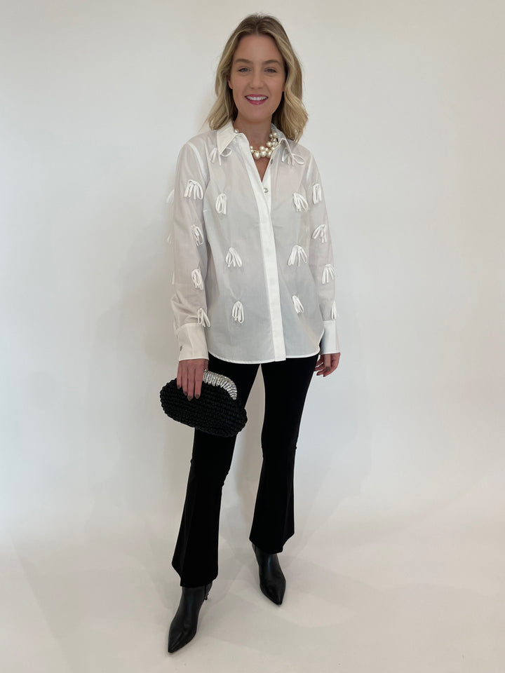 Hope For Flowers Bow Button Down Shirt in White paired with Peace of Cloth Ella Paramount Knit Pants in Black, Vanessa Baroni Multi Beads Collar Necklace in Pearl, Noam Hazan Metallic Desor Clutch in Black available at Barbara Katz