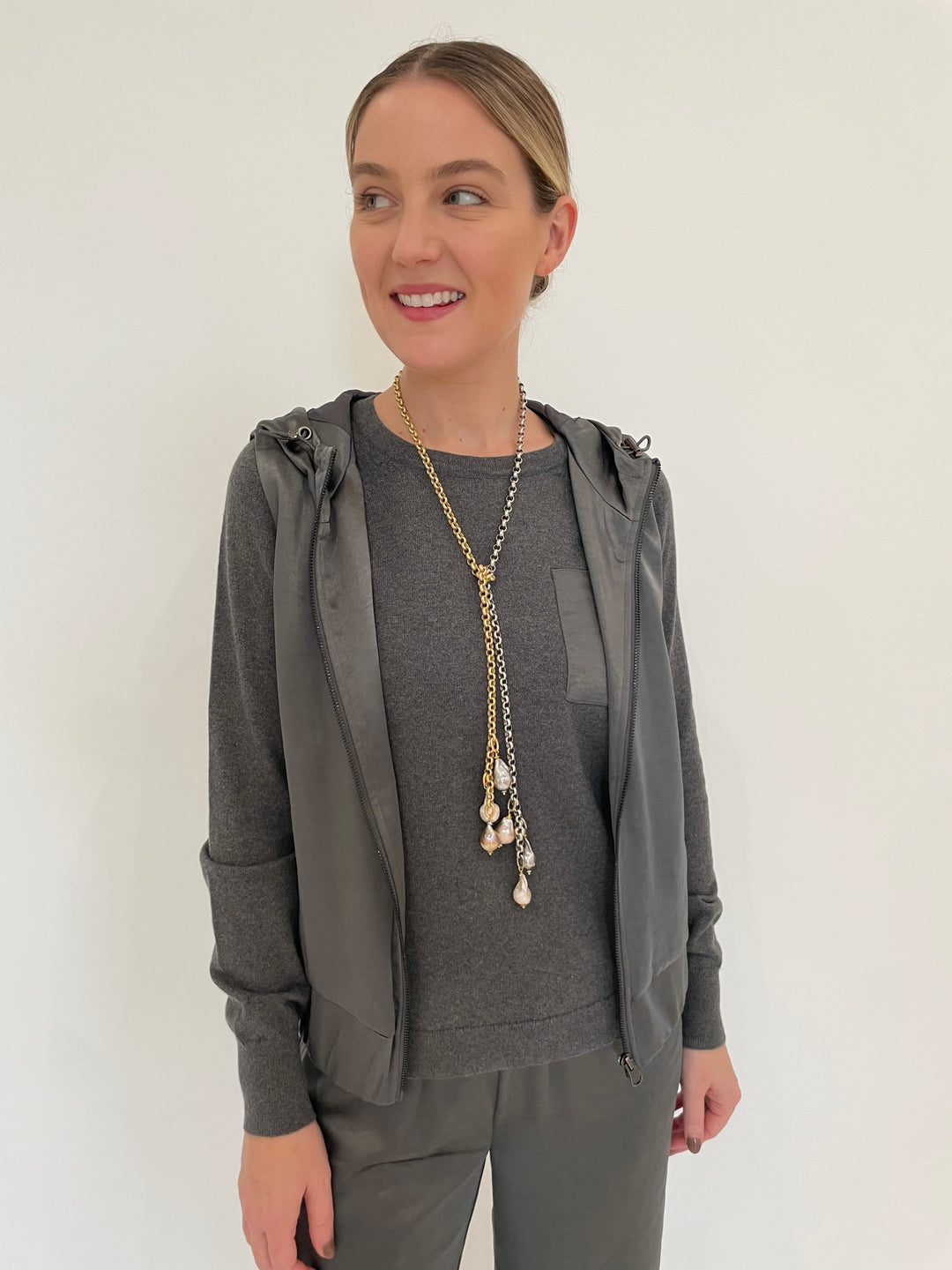 J Society Celeste Satin Hoodie Vest in Gunmetal with Jette Satin Pocket Sweatshirt underneath, paired with matching J Society Jesse Satin Pants in Gunmetal, Suzy T Pearl Lariat Necklace in Gold/Silver available at Barbara Katz