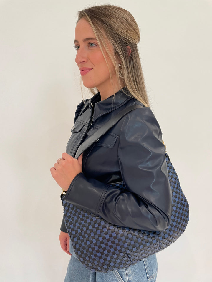 Simkhai Wyatt Vegan Leather Long Sleeve Jacket in Midnight with BK Cata Geometric Shape Metal Earrings in Rhodium, and Clare V Moyen Messenger Bag in Dark Blue Woven Checker - all available at Barbara Katz