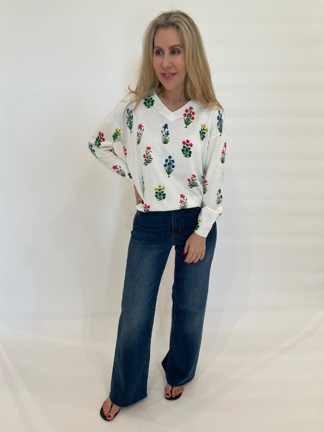 Vilagallo Jazmin V-Neck Floral Sweater in White/Multi paired with Frame Denim Le Slim Palazzo Raw After Jeans in Lupine available at Barbara Katz