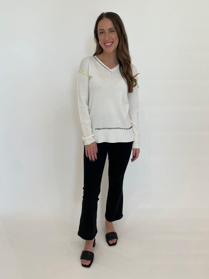 Pure Amici Mona Stitch V-Neck Sweater in White paired with Frame Jetset Crop Mini Boot Jeans in Sheen Noir available at Barbara Katz