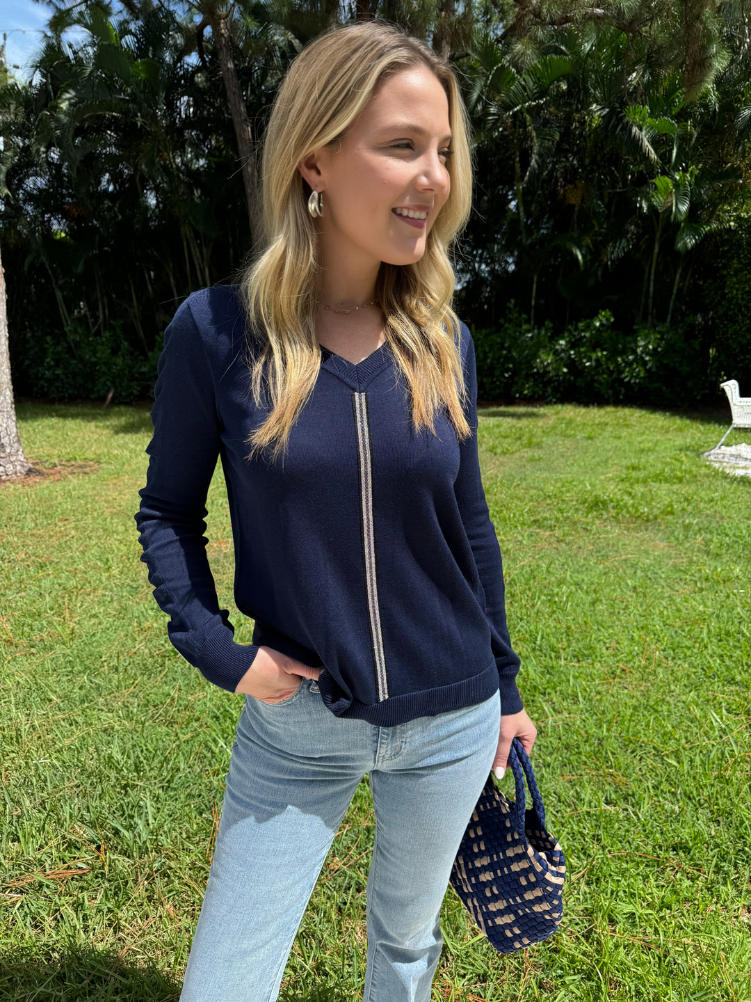 Peace of Cloth V-Neck Sweater With Ribbon Ruched Sleeve in Navy paired with Frame Le Easy Flare Raw Fray Jeans and Sol and Selene Sky's The Limit Small Tote Bag in Navy/Nude