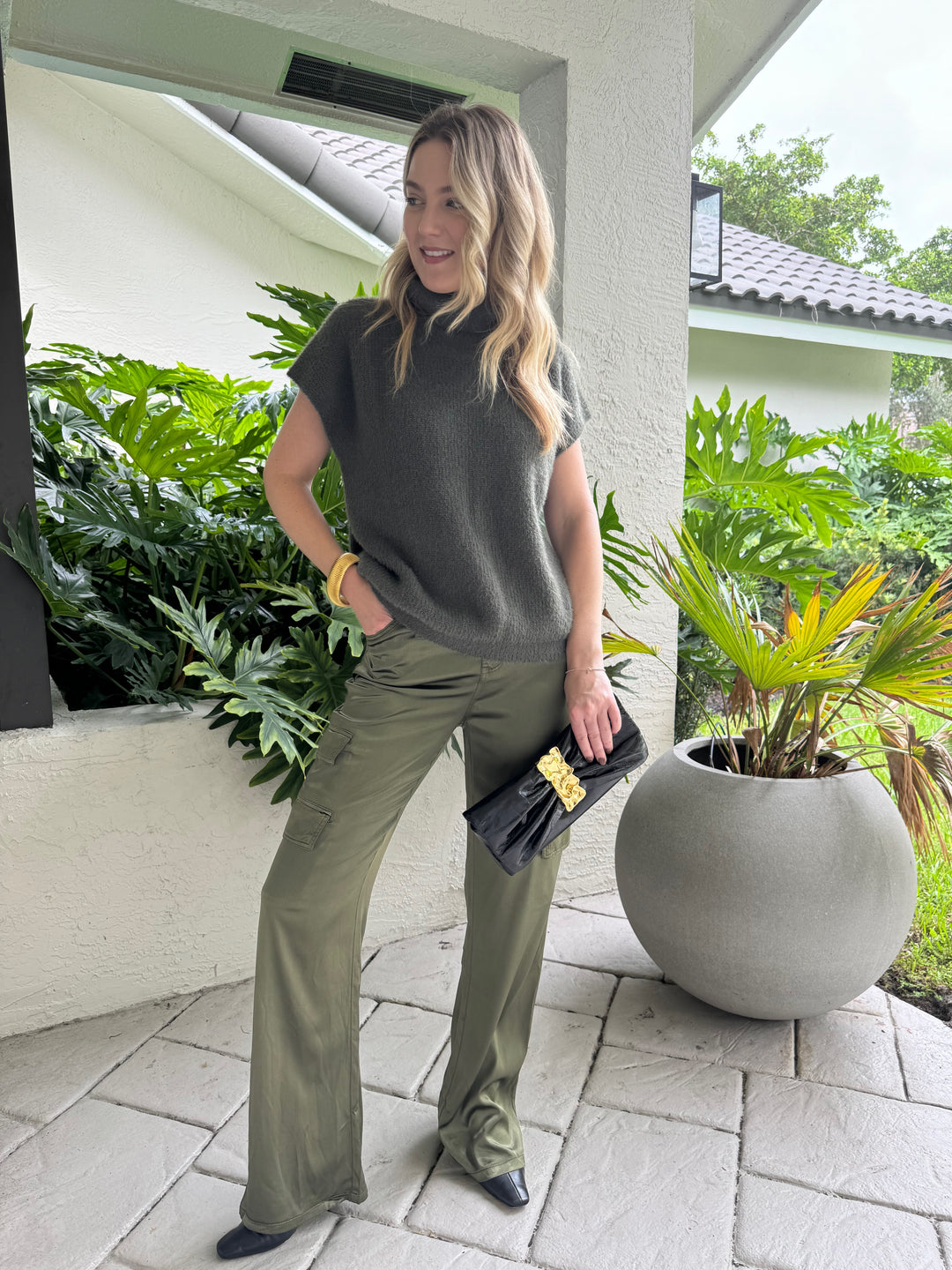 Melissa Nepton Jack Turtleneck Sweater in Winter Moss paired with Marrakech Zendaya Silky Cargo Pants in Pine, BK Gold Cobra Bracelet, and Alexis Bittar Gold Ribbon Convertible Shoulder Bag in Black - all available at Barbara Katz