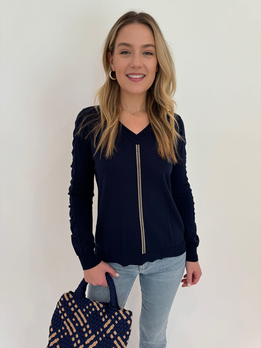 Peace of Cloth V-Neck Sweater With Ribbon Ruched Sleeve in Navy paired with Frame Le Easy Flare Raw Fray Jeans and Sol and Selene Sky's The Limit Small Tote Bag in Navy/Nude