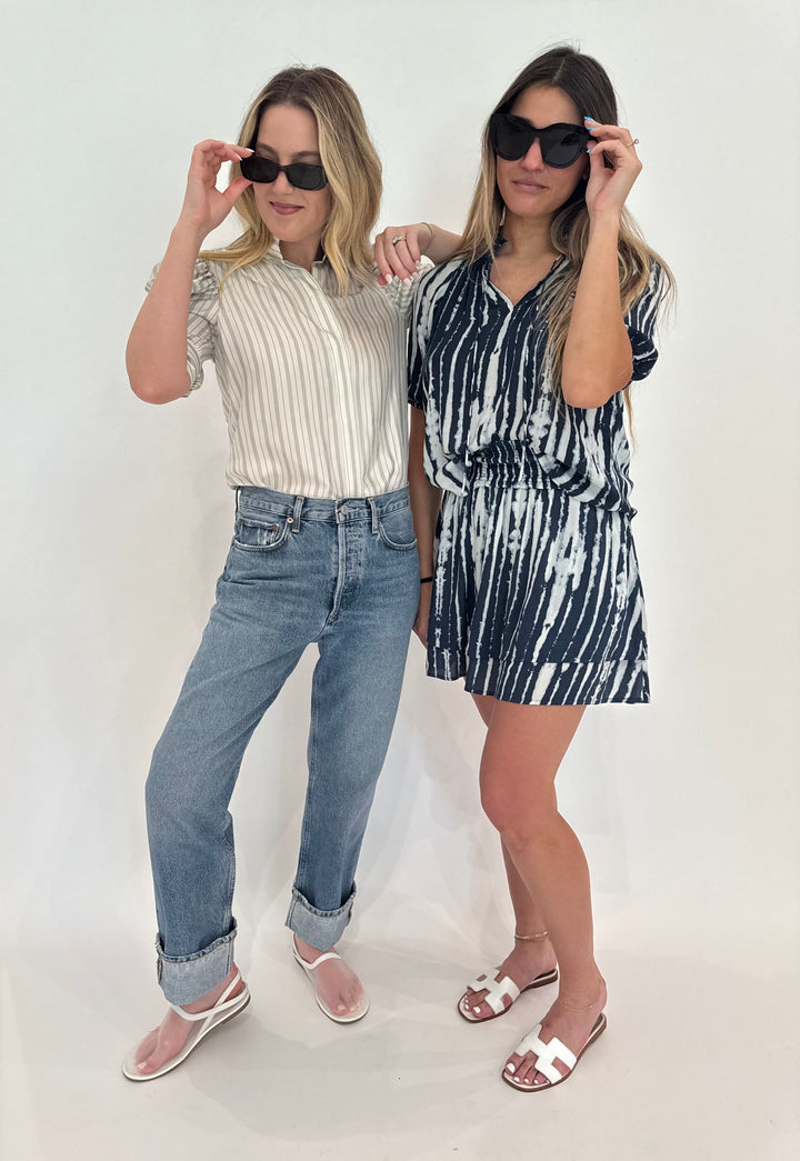 Two models shown wearing Frame Gillian Top in Cream Multi paired with Agolde Fran Jeans and Rails Laila Top paired with Addison Skirt in Indigo Nile