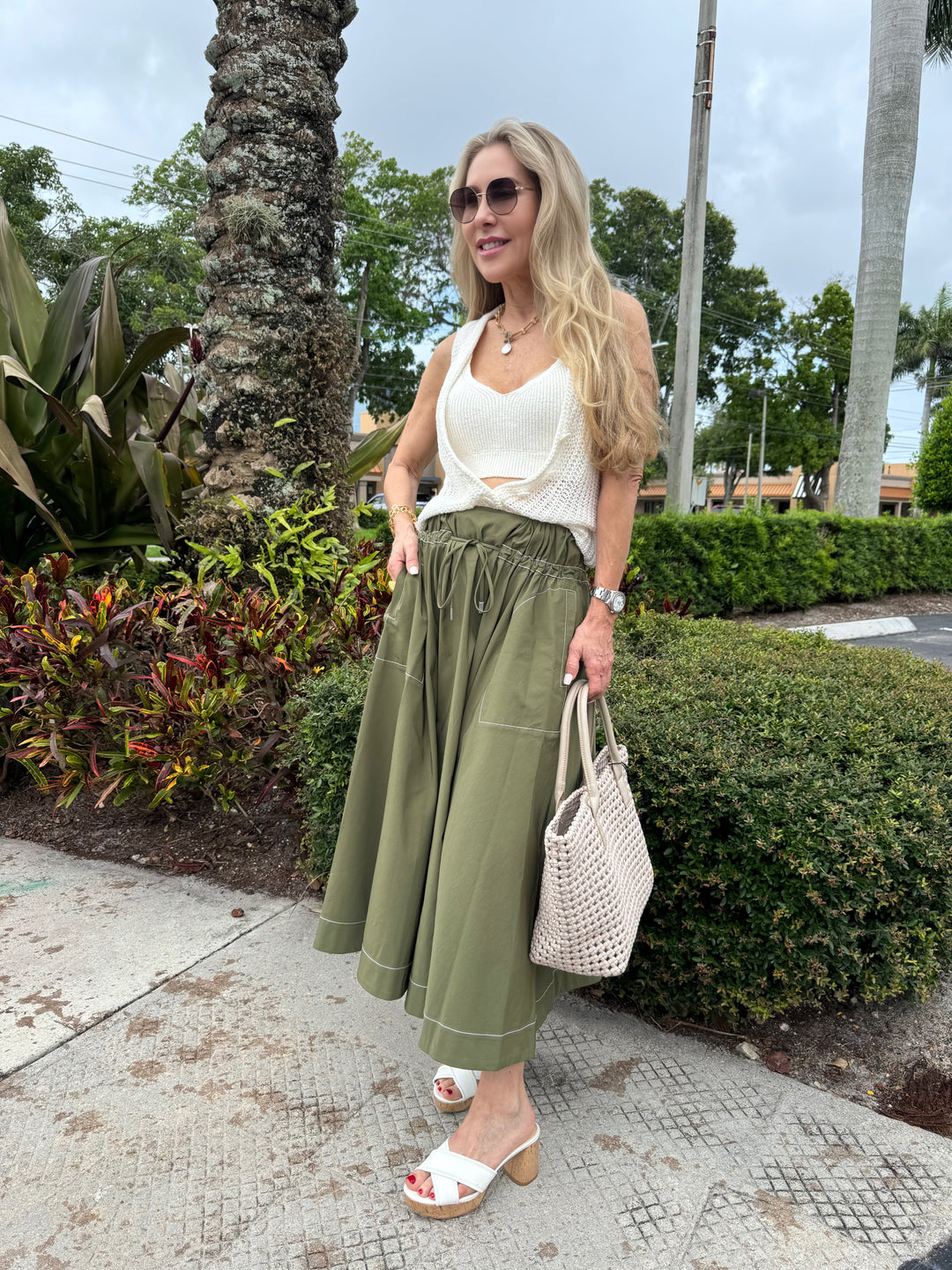 Model wearing Simkhai Tona Midi Skirt in Army Green paired with Enza Costa Linen Open Knit Vest and Bralette in White, Daniella Lehavi Vivian Woven Large Tote Bag