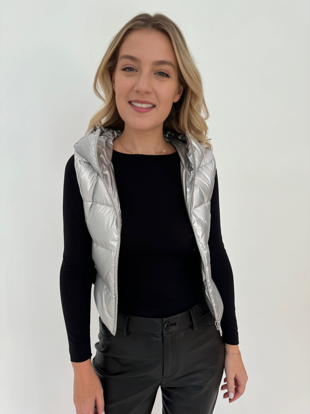 Adroit Atelier Lola Quilted Full Zip Vest in Silver with AMB Black Solid Raw Edge High Neck Second Skin Top underneath, paired with Peace of Cloth Black Faux Leather Slim Jeans, all available at Barbara Katz